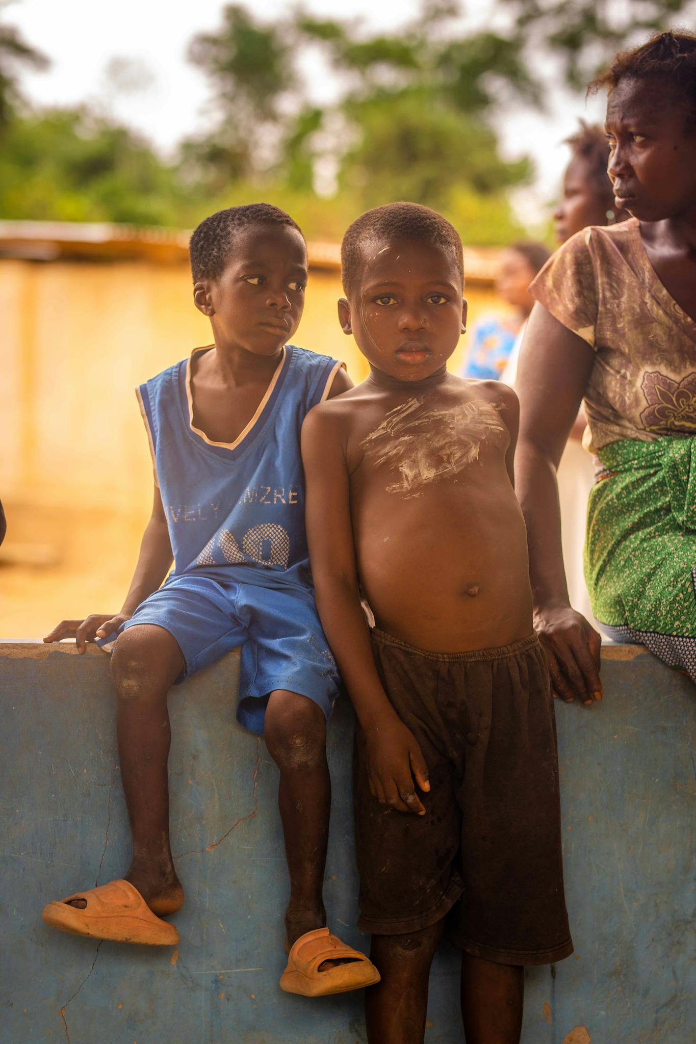 A candid photo capturing children and an adult standing outdoors in a rural environment.