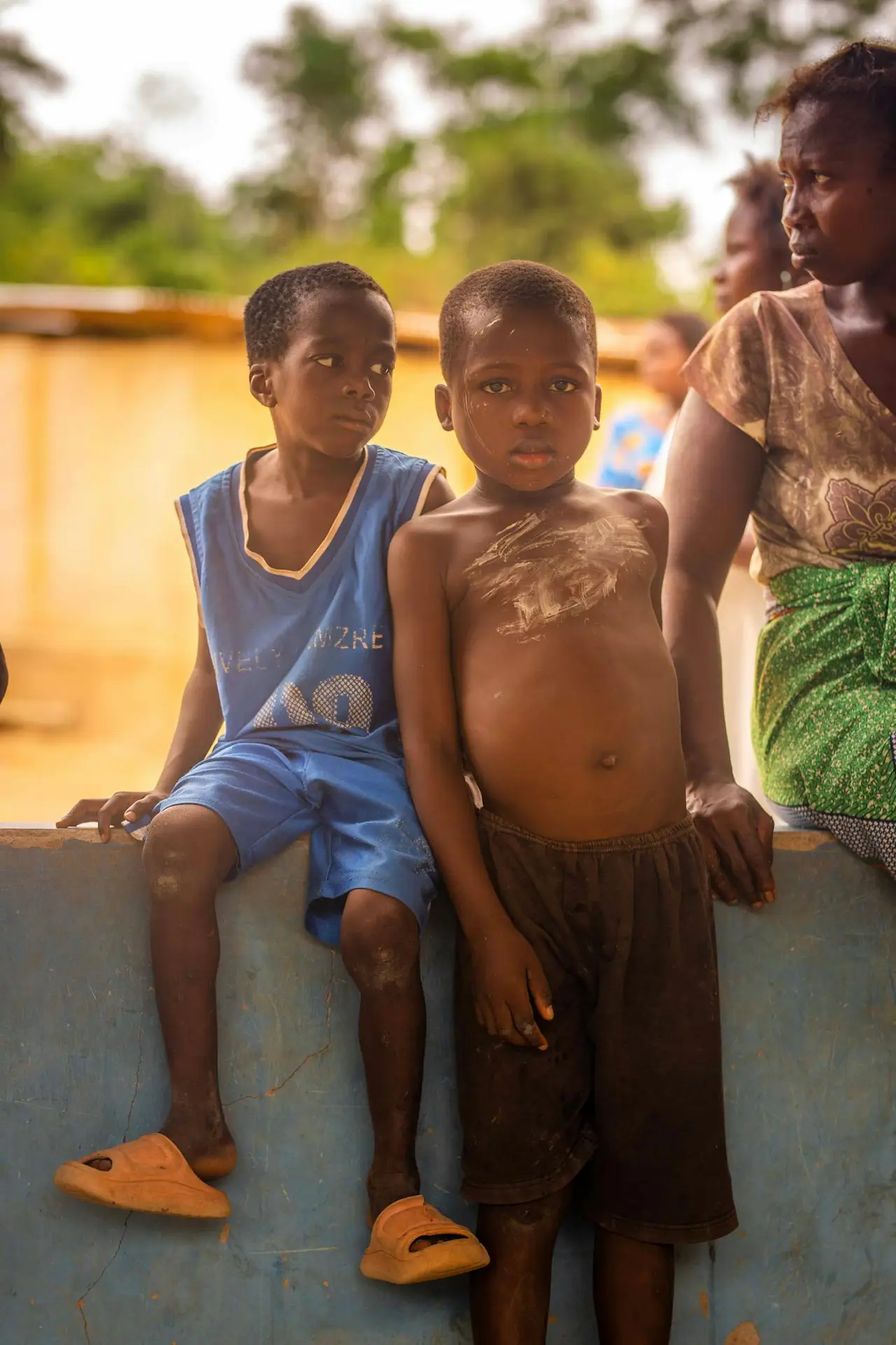 A candid photo capturing children and an adult standing outdoors in a rural environment.